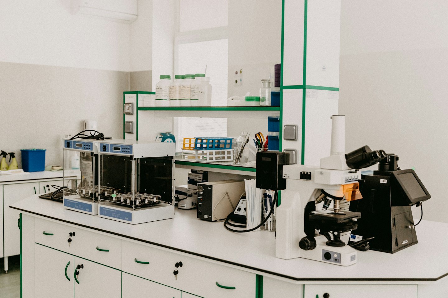 A modern lab with shakers and a microscope on white benches.